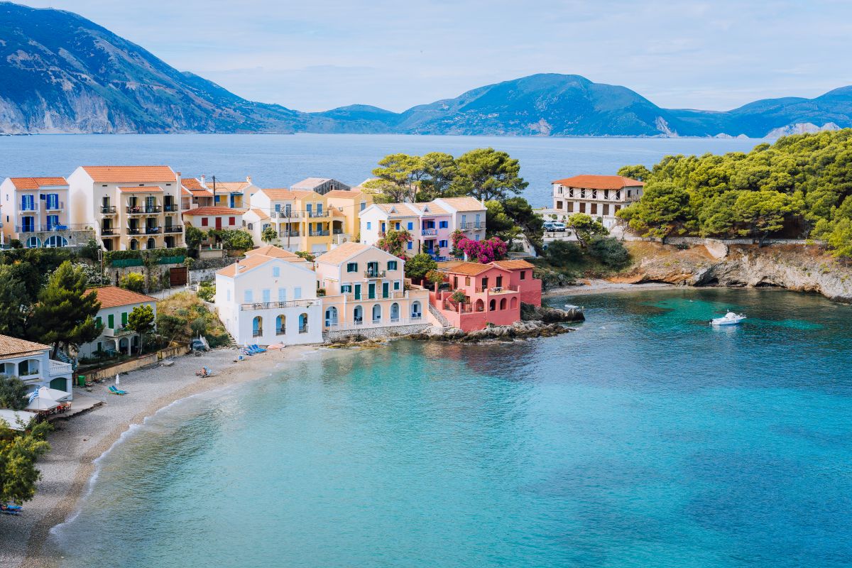 Cute blue sea bay in front of Assos village. Beautiful view to vivid colorful houses near blue turquoise colored transparent bay lagoon. Kefalonia, Greece